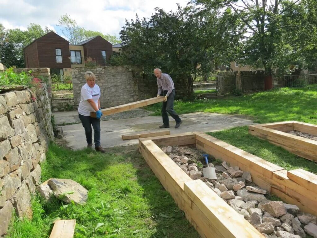 Two people carrying one of the long blocks into place