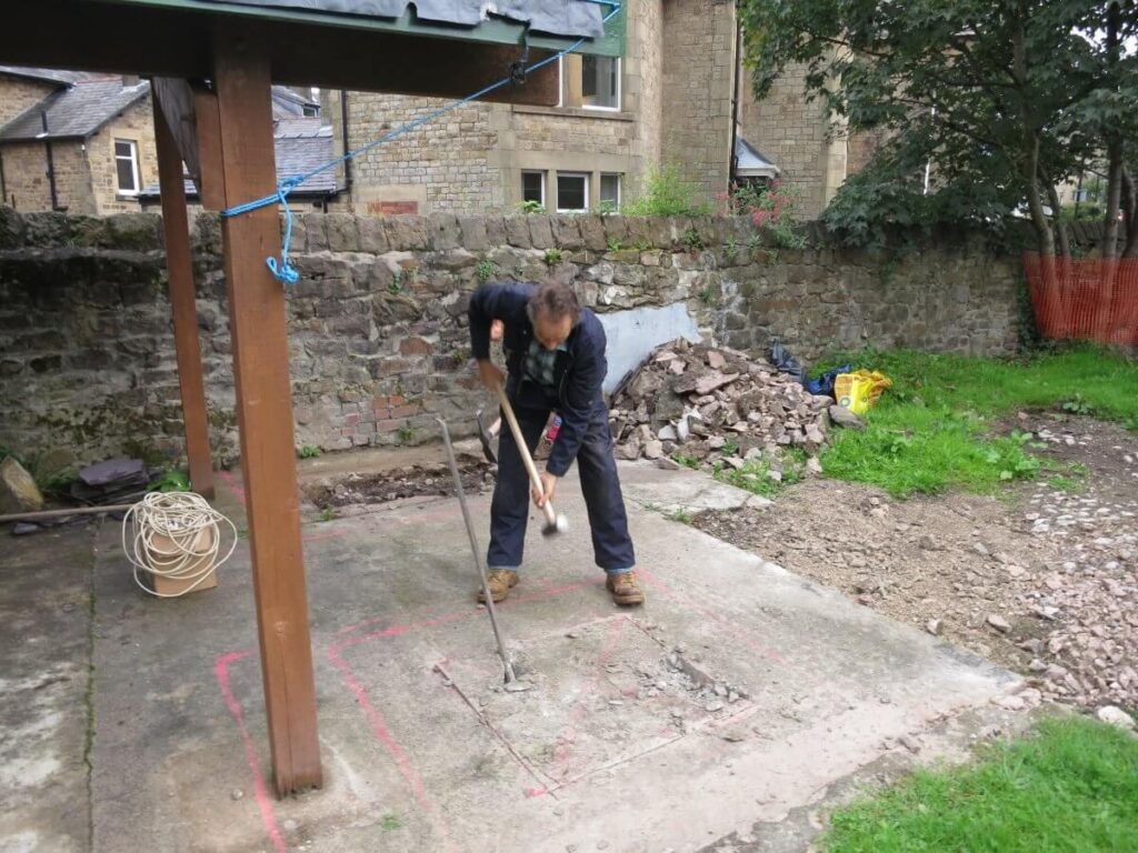 Smashing up some of the concrete ground with a large mallet