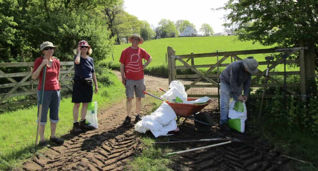 Volunteers by gate with wheelbarrow