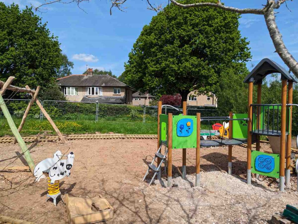 Toddlers area of the playground with equipment but bare earth on the ground